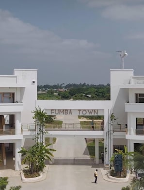 Un edificio moderno con la segnaletica 'FUMBA TOWN', una pensilina e una persona che cammina.