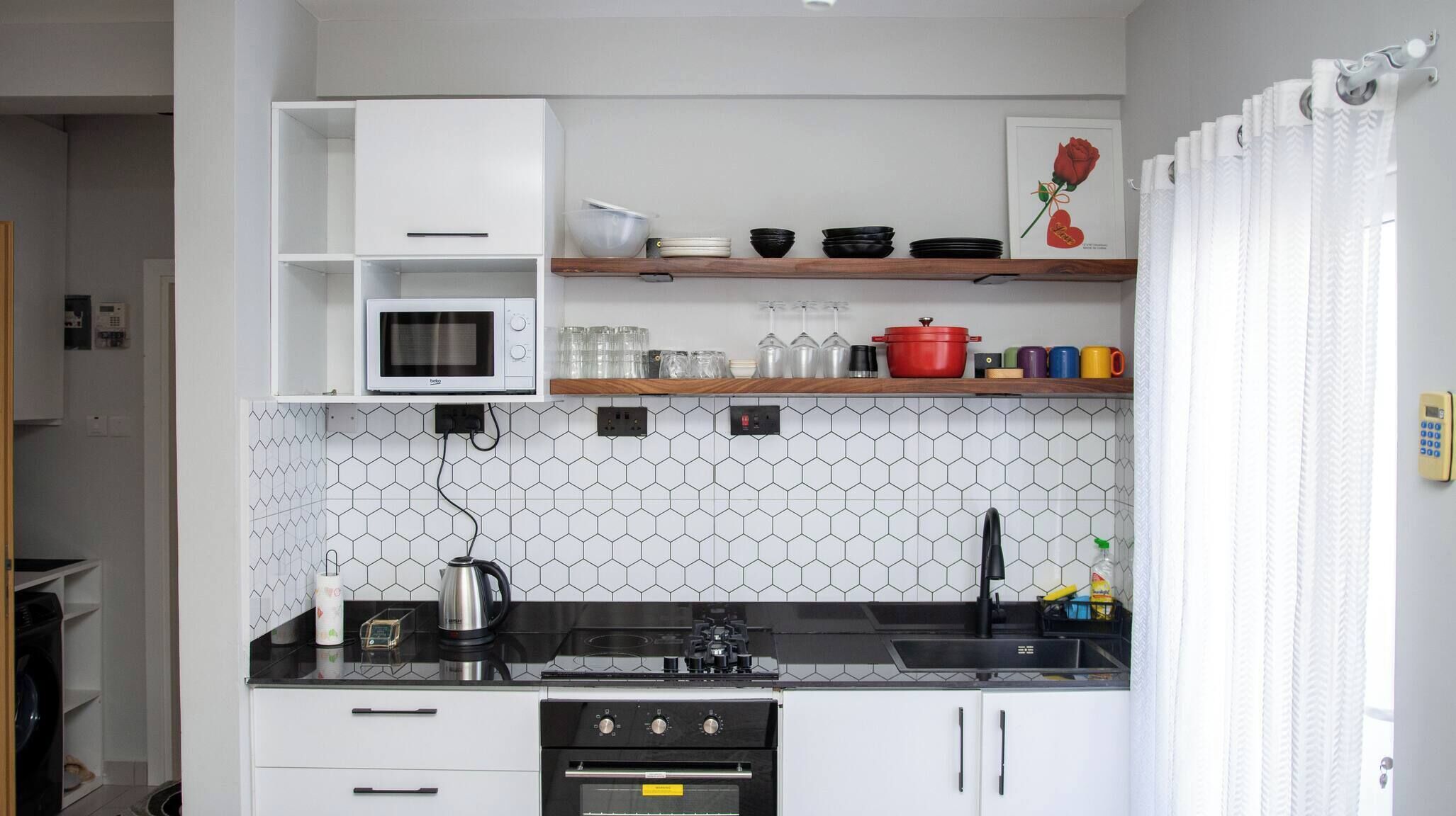 Una cucina compatta con microonde, fornello, forno e macchina da caffè.
