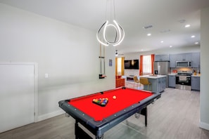 Un espace de vie moderne comprenant une table de billard, un coin cuisine et un coin repas.