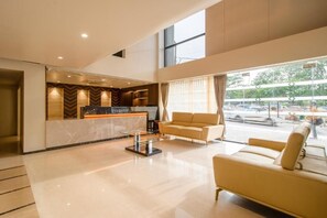 Un vestíbulo de hotel con mostrador de recepción, un sofá y una mesa de centro.