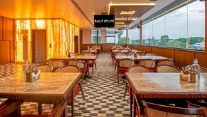 Un restaurante con suelo de cuadros, mesas y sillas de madera, y un ventanal con vistas.