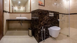Un baño moderno con tocador de mármol, inodoro y ducha con mampara de vidrio.