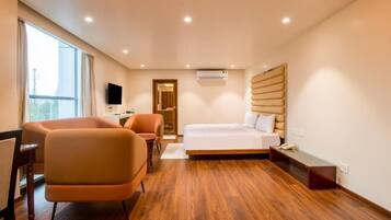 A hotel room with a bed, a desk, a chair, and a television.