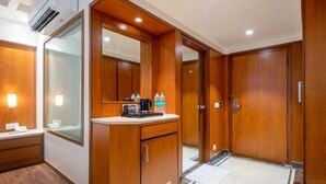 A hotel bathroom with wooden cabinetry, a mirror, a sink, and a countertop with toiletries.