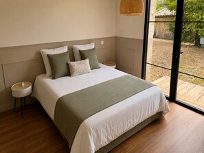 A bedroom with a large bed, a bedside table, a hanging light, and a view of the outdoors. - Villa with pool, sleeps 8, 4,500 m² garden, Bordeaux (Latresne)