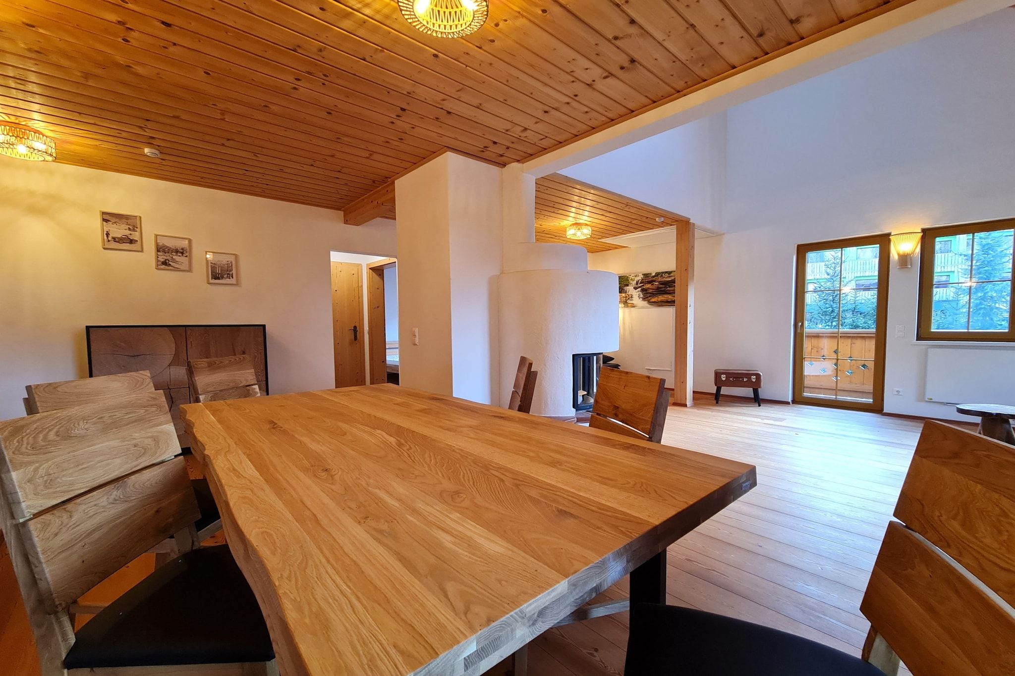 A spacious room with a large wooden dining table, chairs, and a wooden ceiling.