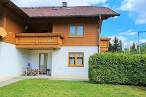 A two-story wooden house with a balcony, a small patio with outdoor furniture, and a well-maintained hedge. - Modern apartment in Bad Kleinkirchheim (Bad Kleinkirchheim)