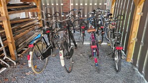 A covered bicycle parking area with multiple bicycles and wooden storage racks.