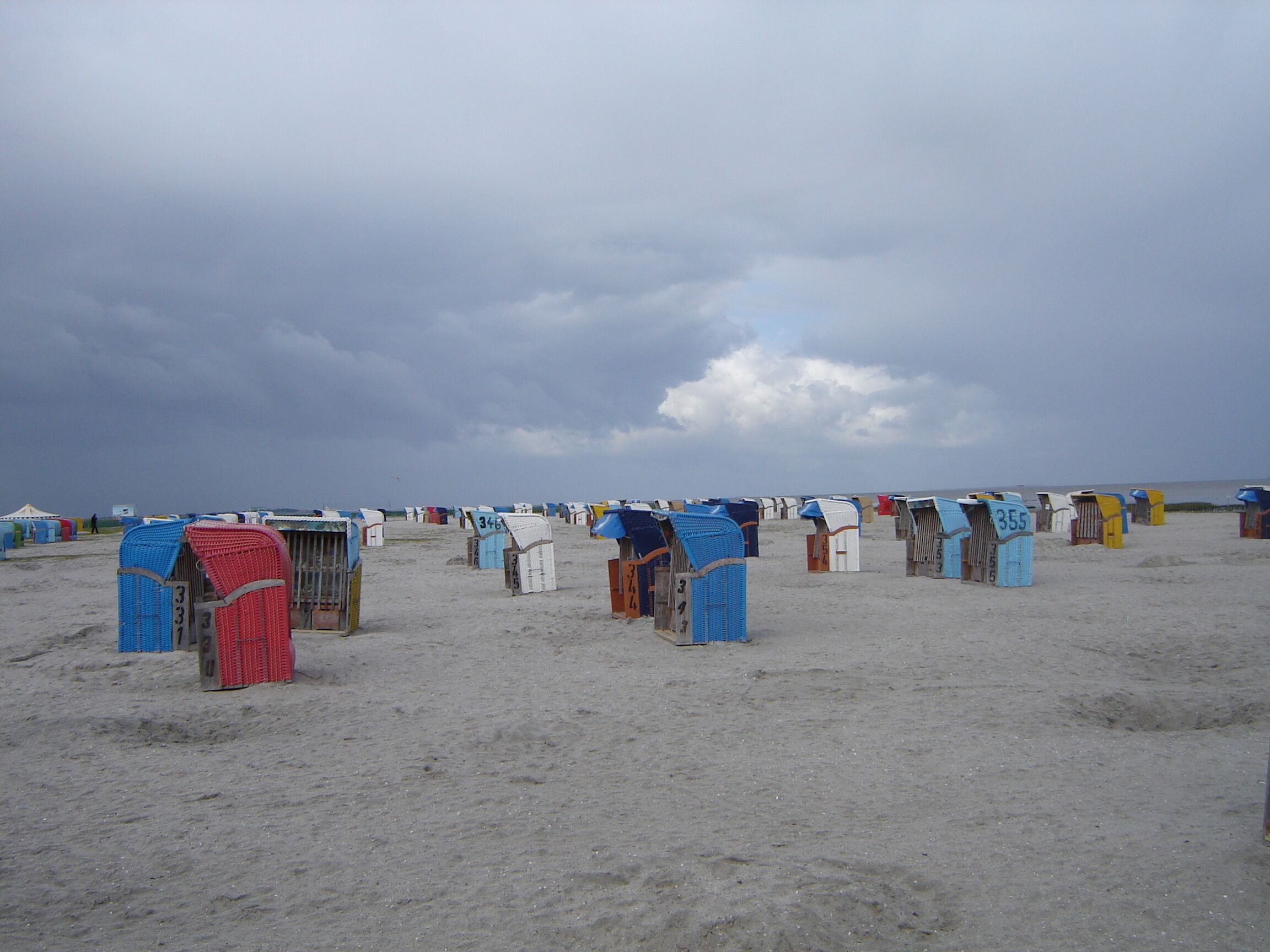 Una playa con numerosas cabañas de playa numeradas y dispuestas en filas.