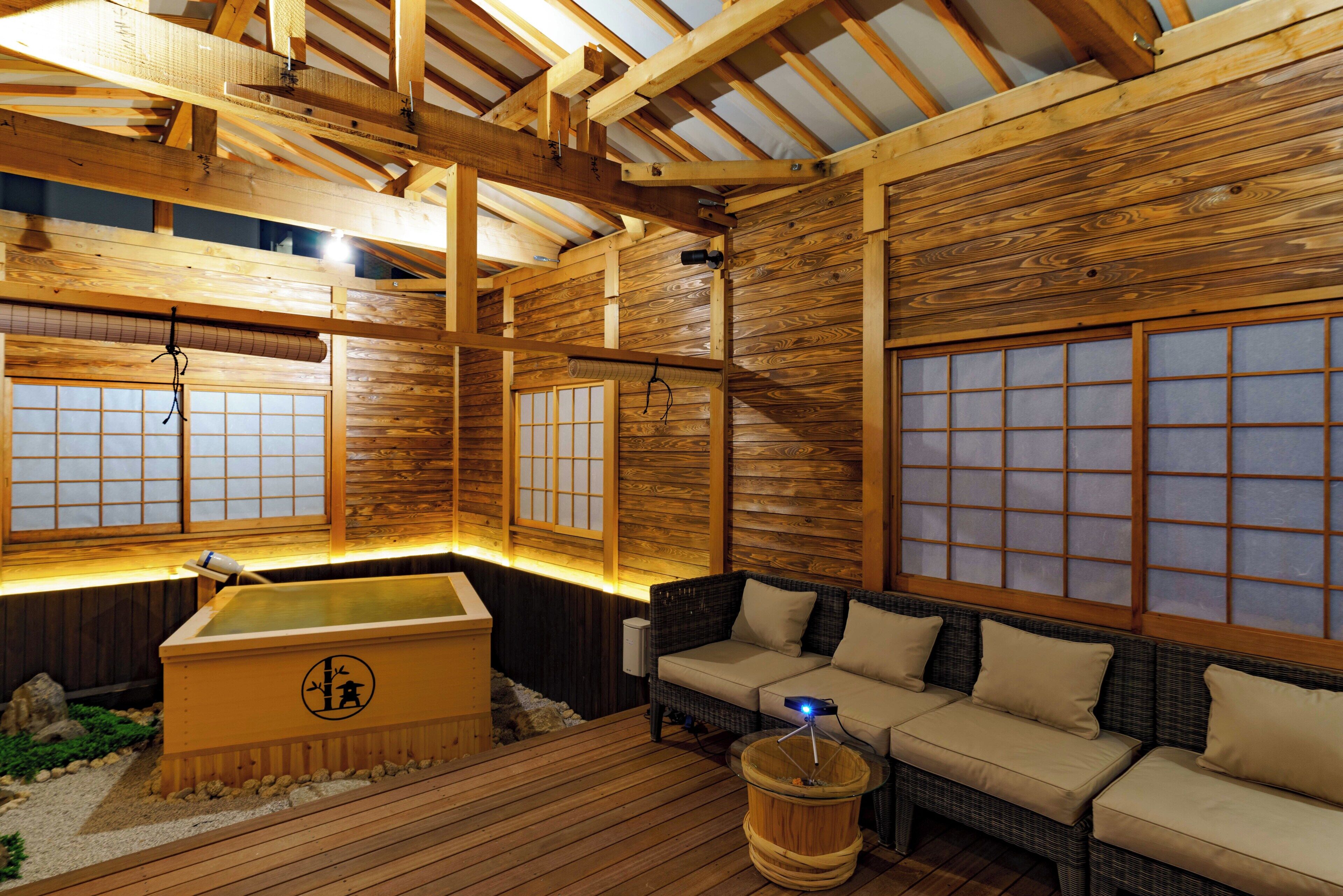 Un onsen japonés tradicional con vigas de madera, suelo de tatami y un sofá de tatami.