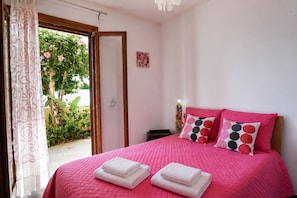 A bedroom with a bed, pillows, and a door leading to an outdoor area.