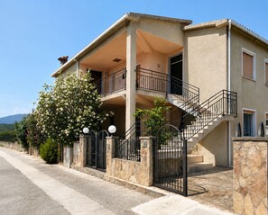 Ein zweigeschossiges Gebäude mit Balkon, Treppe und einem verschlossenen Eingang.