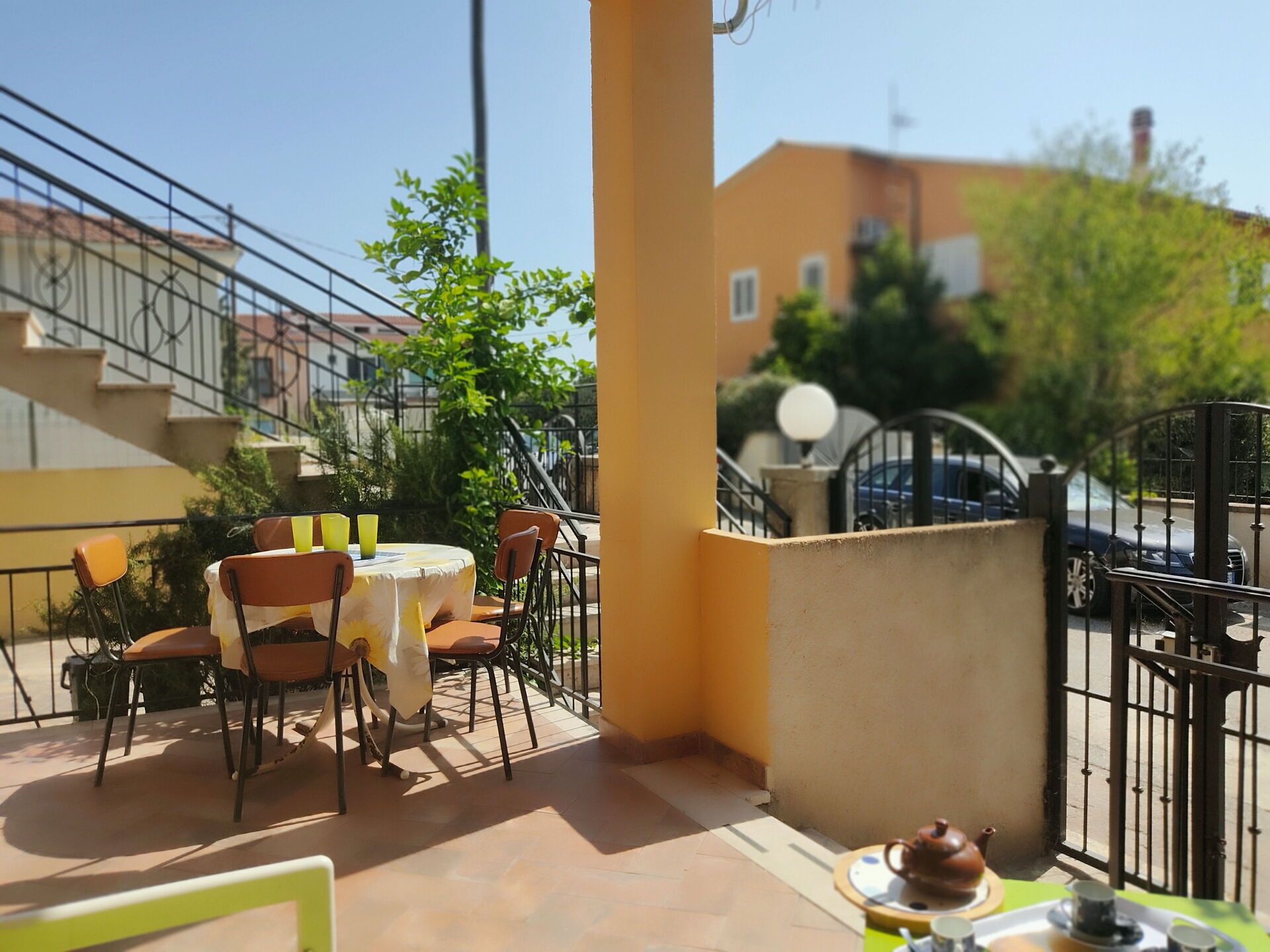 An outdoor seating area with a table and chairs, a teapot, and a cup on a tray.