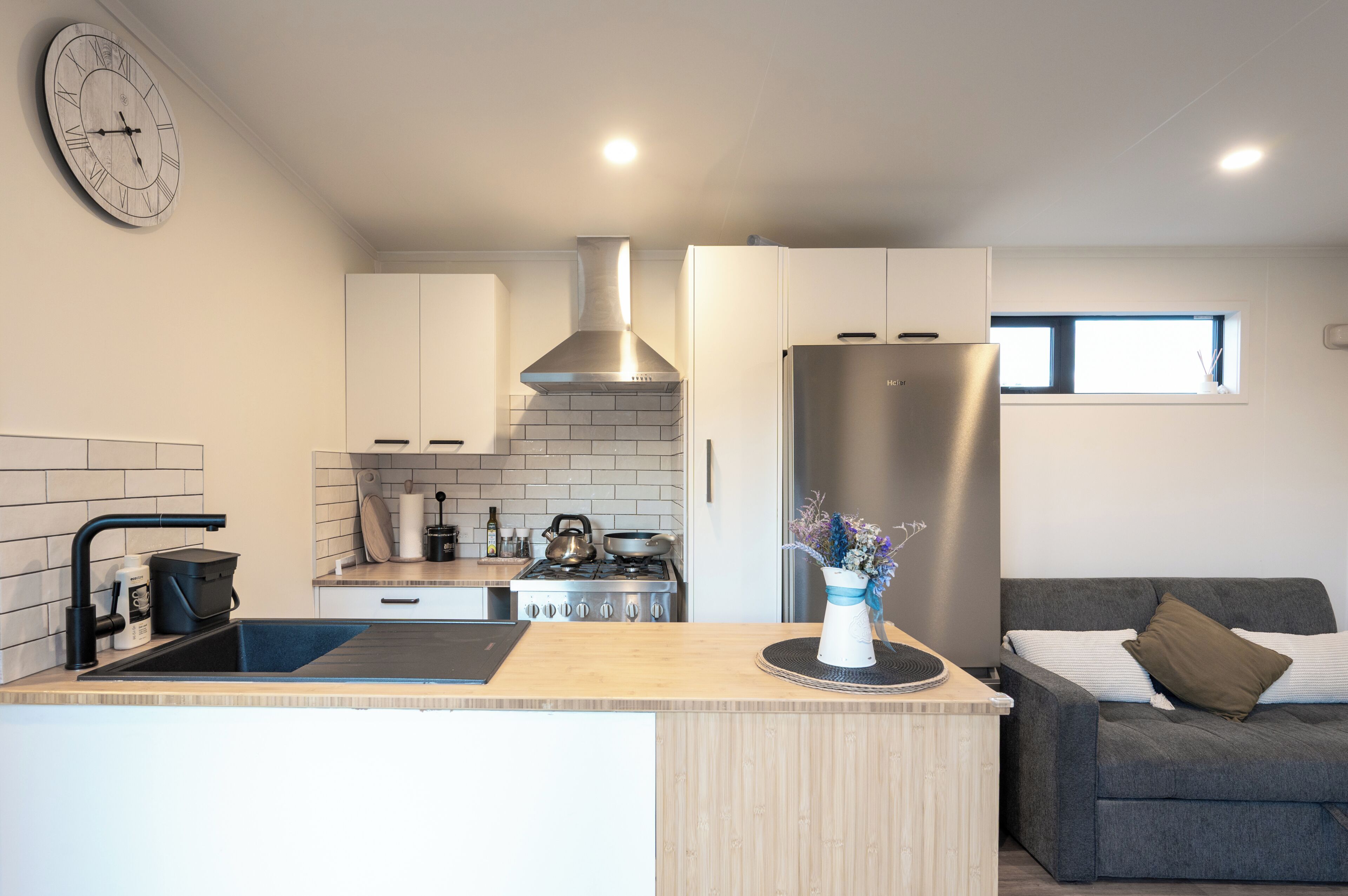A modern kitchen with white cabinets, a stainless steel range hood, and a built-in oven.