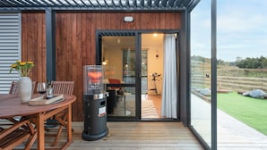 Eine Holzterrasse mit Tisch, Stühlen, einem Grill und Blick ins Freie.