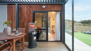 A wooden deck with a table and chairs, a grill, and a view of the outdoors.