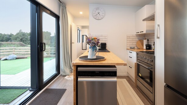 A modern kitchen with a dishwasher, stove, and a clock on the wall.