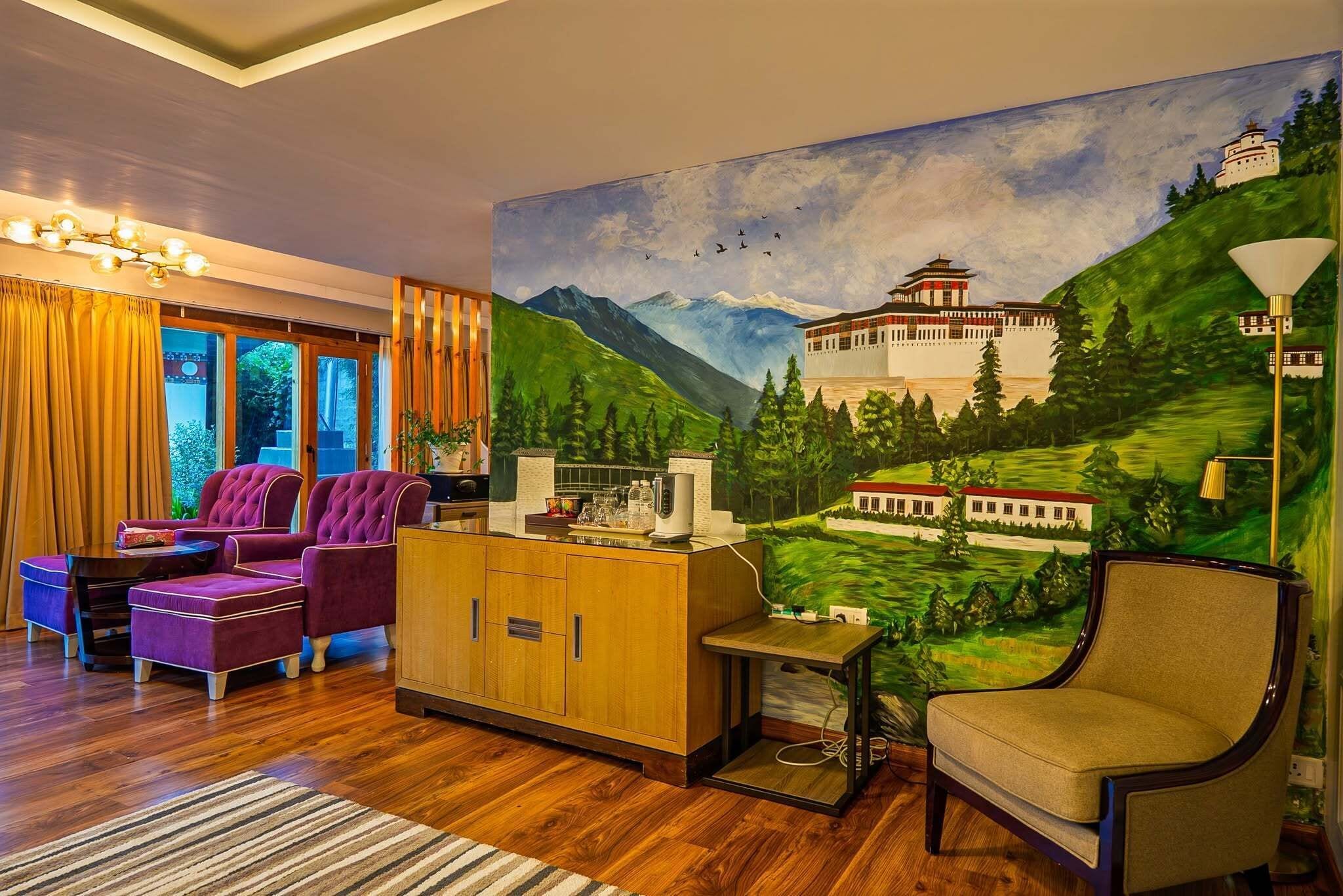 A living room with a large painting of a mountainous landscape, a purple sofa set, a wooden cabinet, and a lamp.