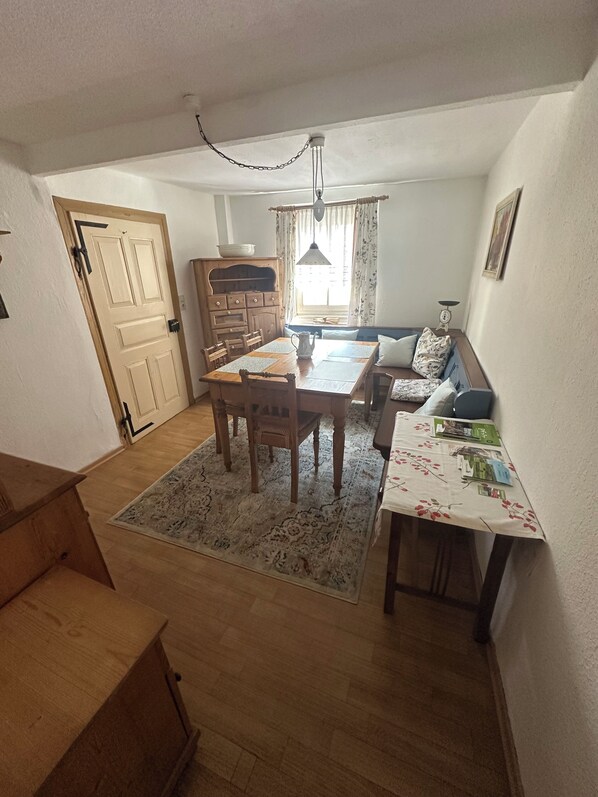 A compact living space with a dining area, a sofa, and a small table with magazines.