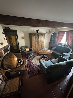 A traditional living room with a globe, armchairs, a wooden cabinet, and a patterned rug.