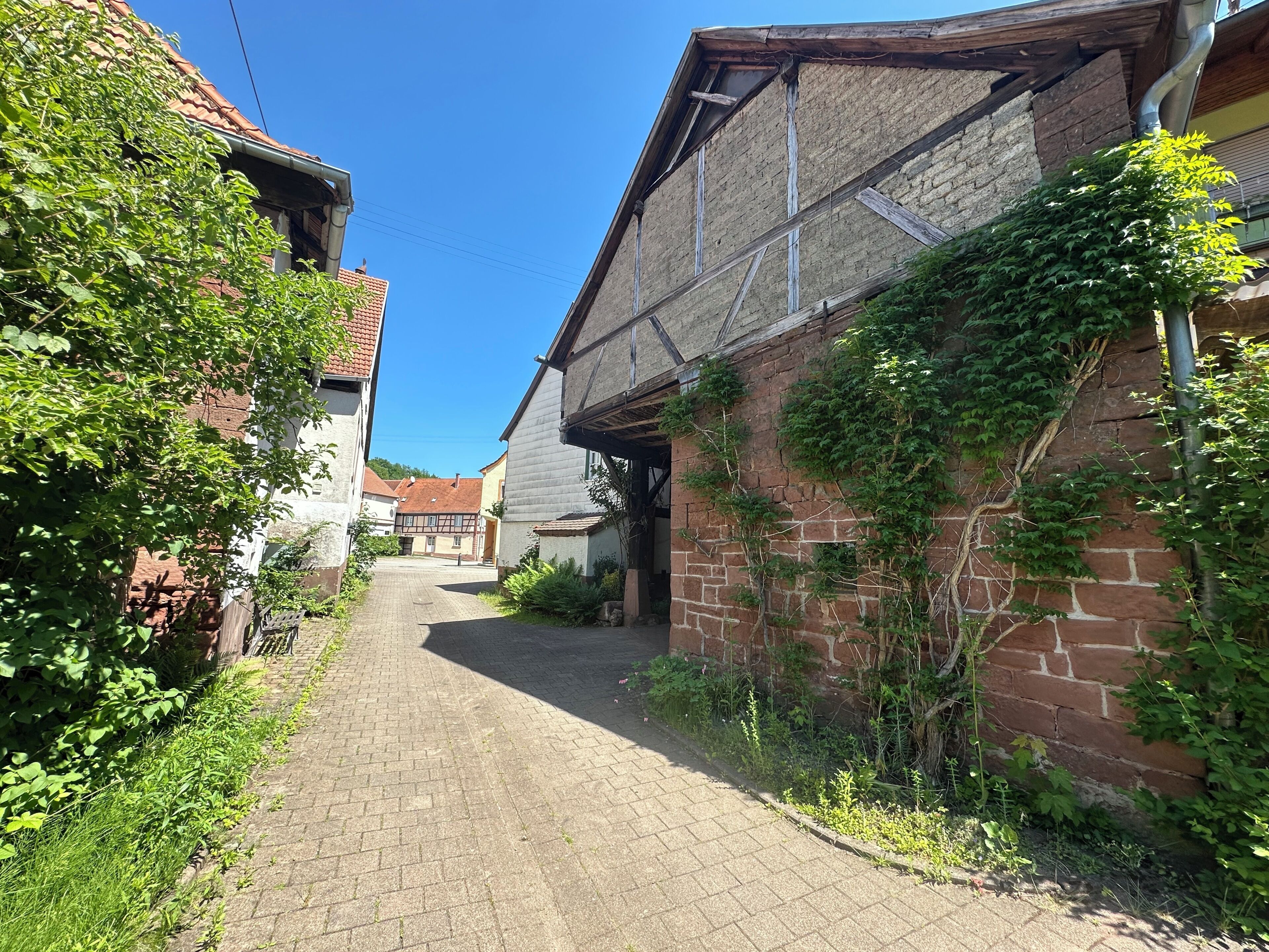 A narrow cobblestone alley with buildings on either side, some with visible brickwork and others with wooden facades.