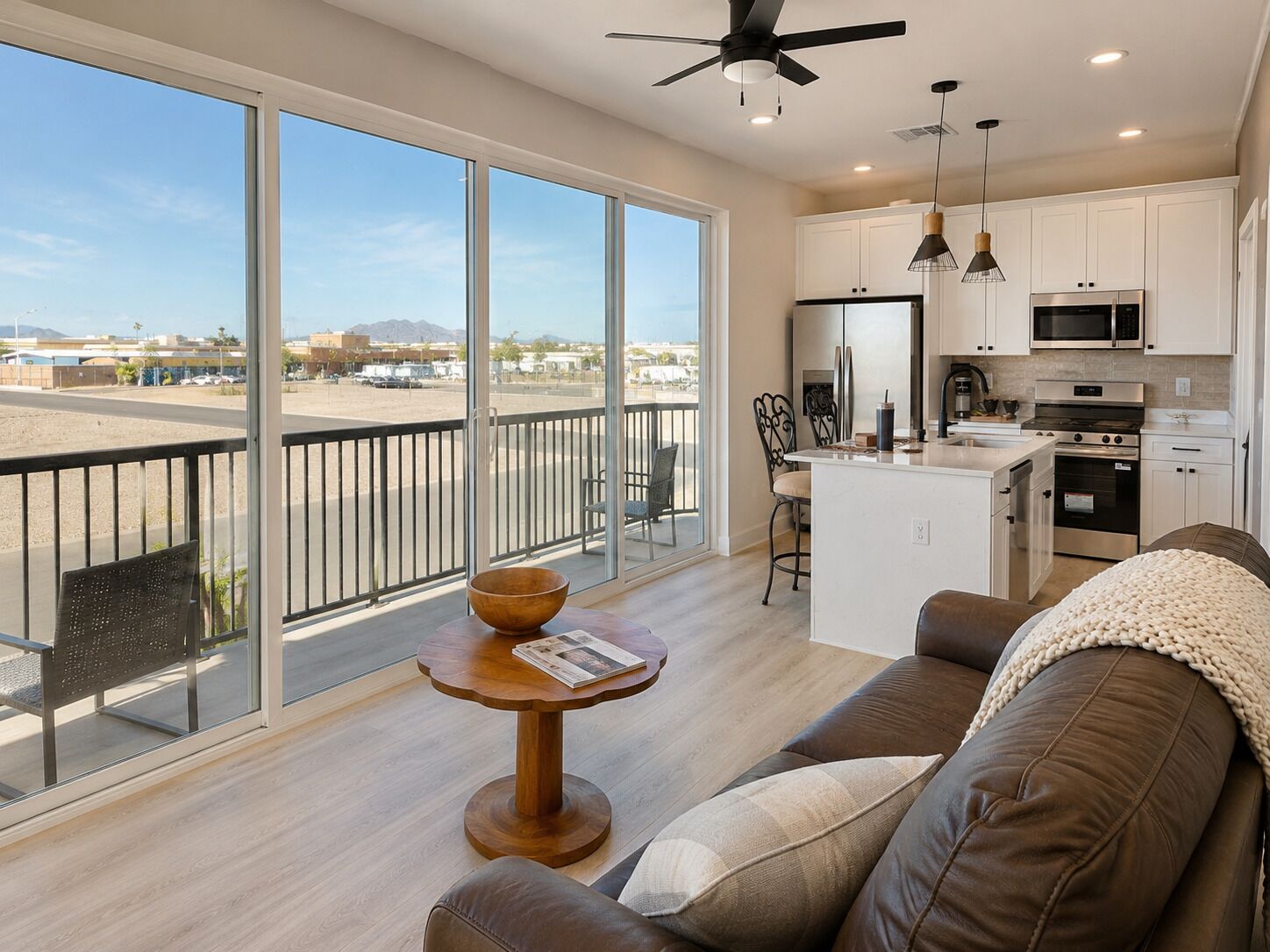 A modern kitchen with white cabinets, stainless steel appliances, and a balcony with a view of the city.