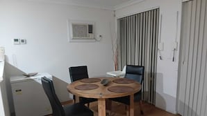 A small dining area with a round wooden table, four chairs, and a refrigerator.
