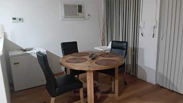 A small dining area with a round wooden table, four chairs, and a refrigerator.