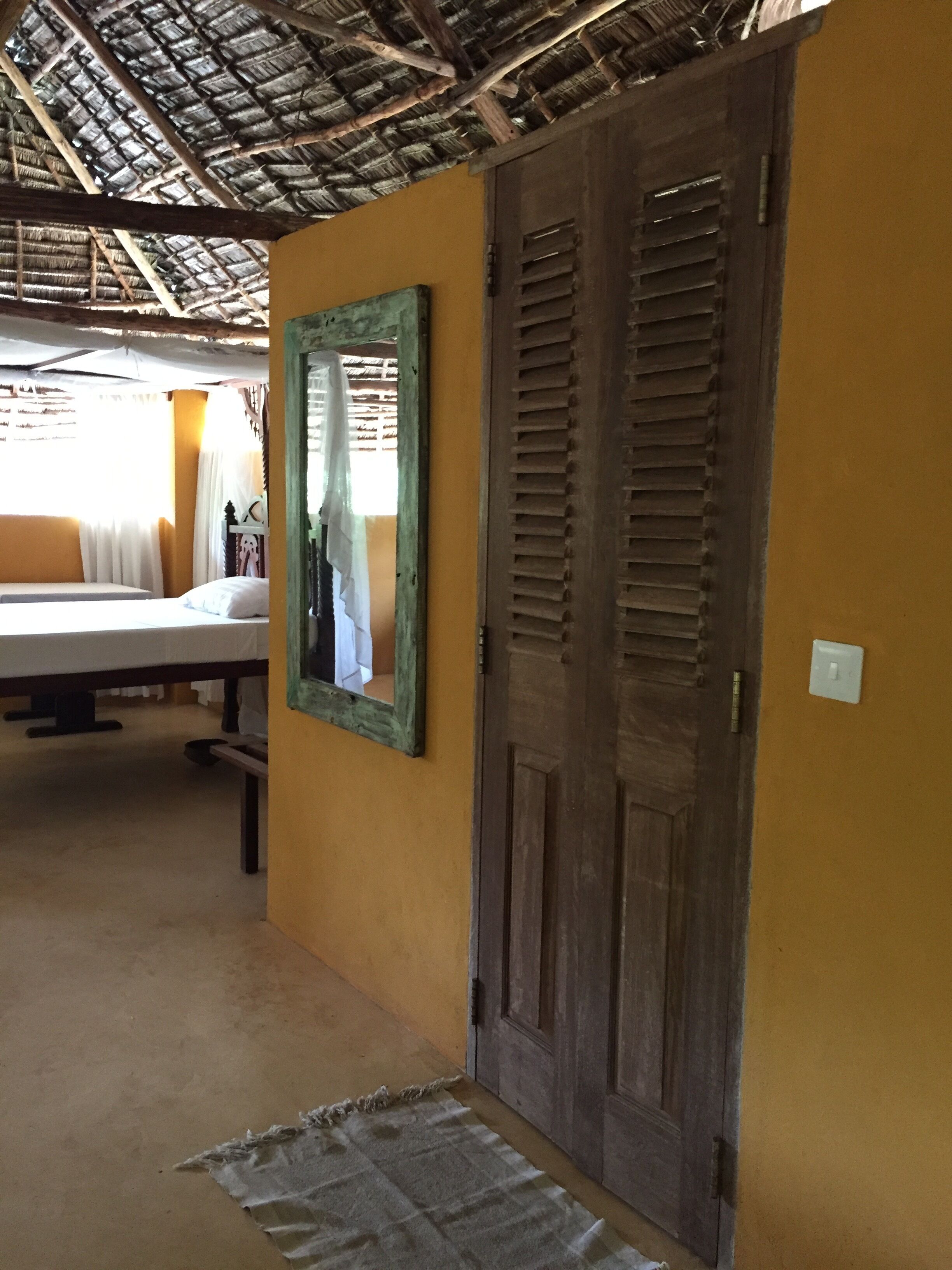 A room with a bed, a mirror, and a wooden door.