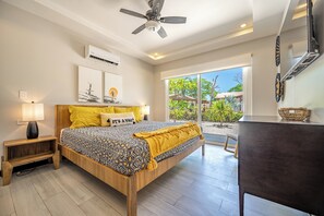 A bedroom with a bed, bedside lamps, a ceiling fan, and a view of the outdoors. - Avellanas Beach Condo: Saltwater Pool Access! (Playa Avellanas)