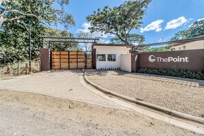 Una entrada con portón a una propiedad, con un camino pavimentado que conduce a un edificio.