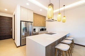 A modern kitchen with a large island, stainless steel appliances, wooden cabinets, and pendant lighting. - Tamarindo Villa w/ Pool & Beach Club Access (Tamarindo)
