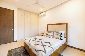 Ein Schlafzimmer mit einem Bett, einem Deckenventilator, einer Klimaanlage und einem Holzschrank.