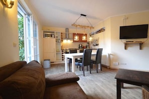A compact living space with a dining area, kitchenette, and a television mounted on the wall. - Holiday apartment with 2 bedrooms (Kölpinsee)