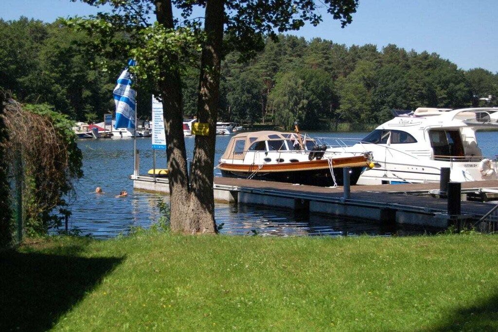 A marina with boats docked, a grassy area, and a tree in the foreground.