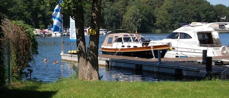 A marina with boats docked, a grassy area, and a tree in the foreground.