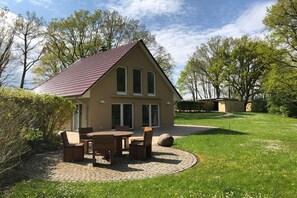 A house with a tiled patio, a dining table with chairs, and a stone pathway leading to the entrance. - 5-star hotel "Fauna & Flora" (Strasen)