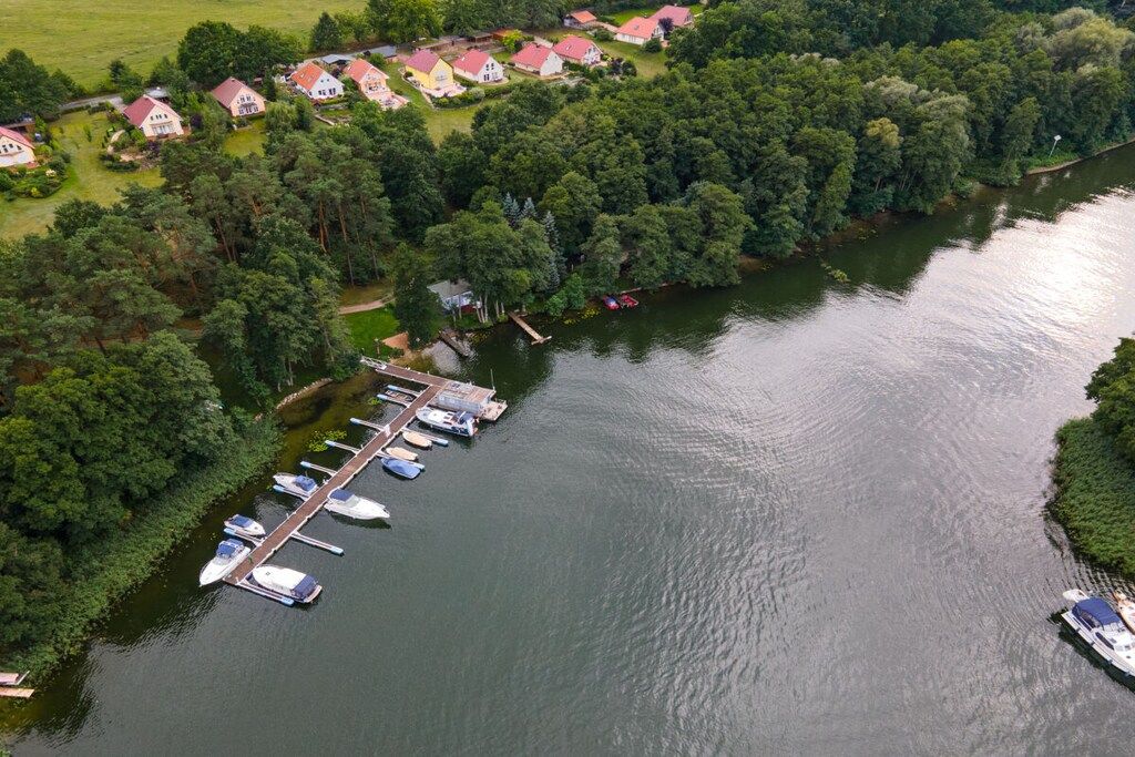 Luftaufnahme eines Sees mit einem Anwesen, einer Marina, Häusern und dichtem Grün.