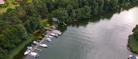 Luftaufnahme eines Sees mit einem Anwesen, einer Marina, Häusern und dichtem Grün.