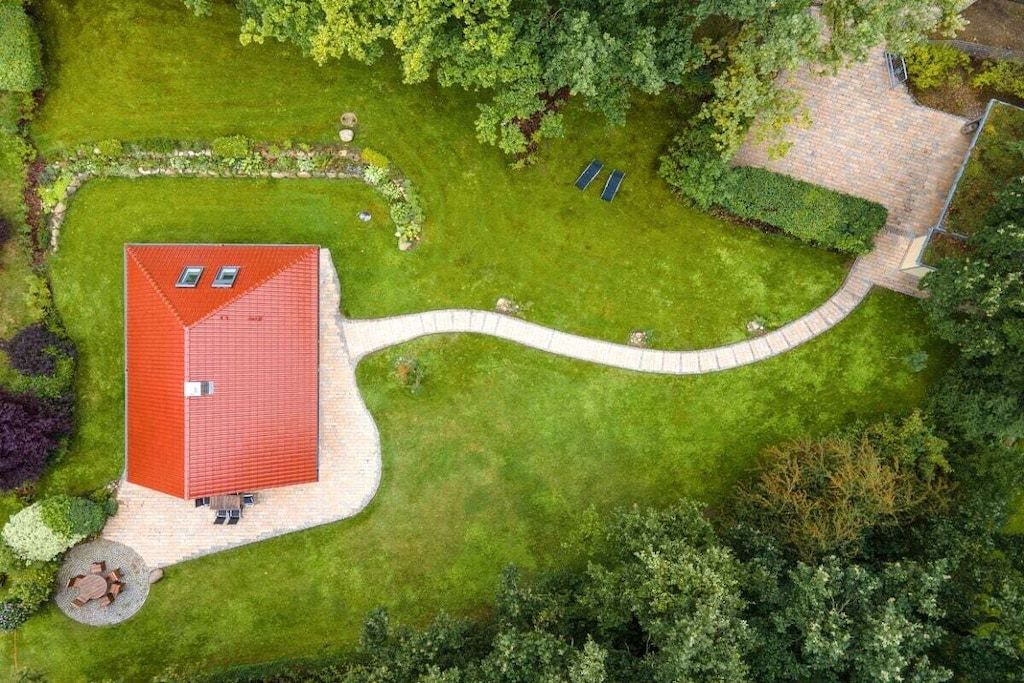 Un edificio de techo rojo con un camino pavimentado y una senda curva que conduce a un césped verde.