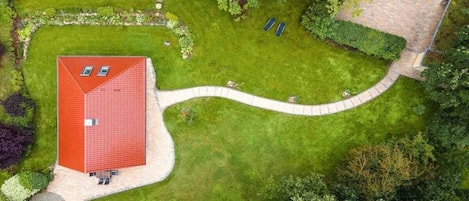Un edificio de techo rojo con un camino pavimentado y una senda curva que conduce a un césped verde.