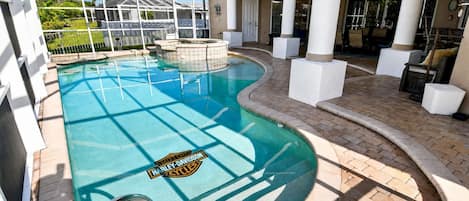 A swimming pool with a Harley-Davidson logo, surrounded by a covered patio area with white columns and outdoor furniture.