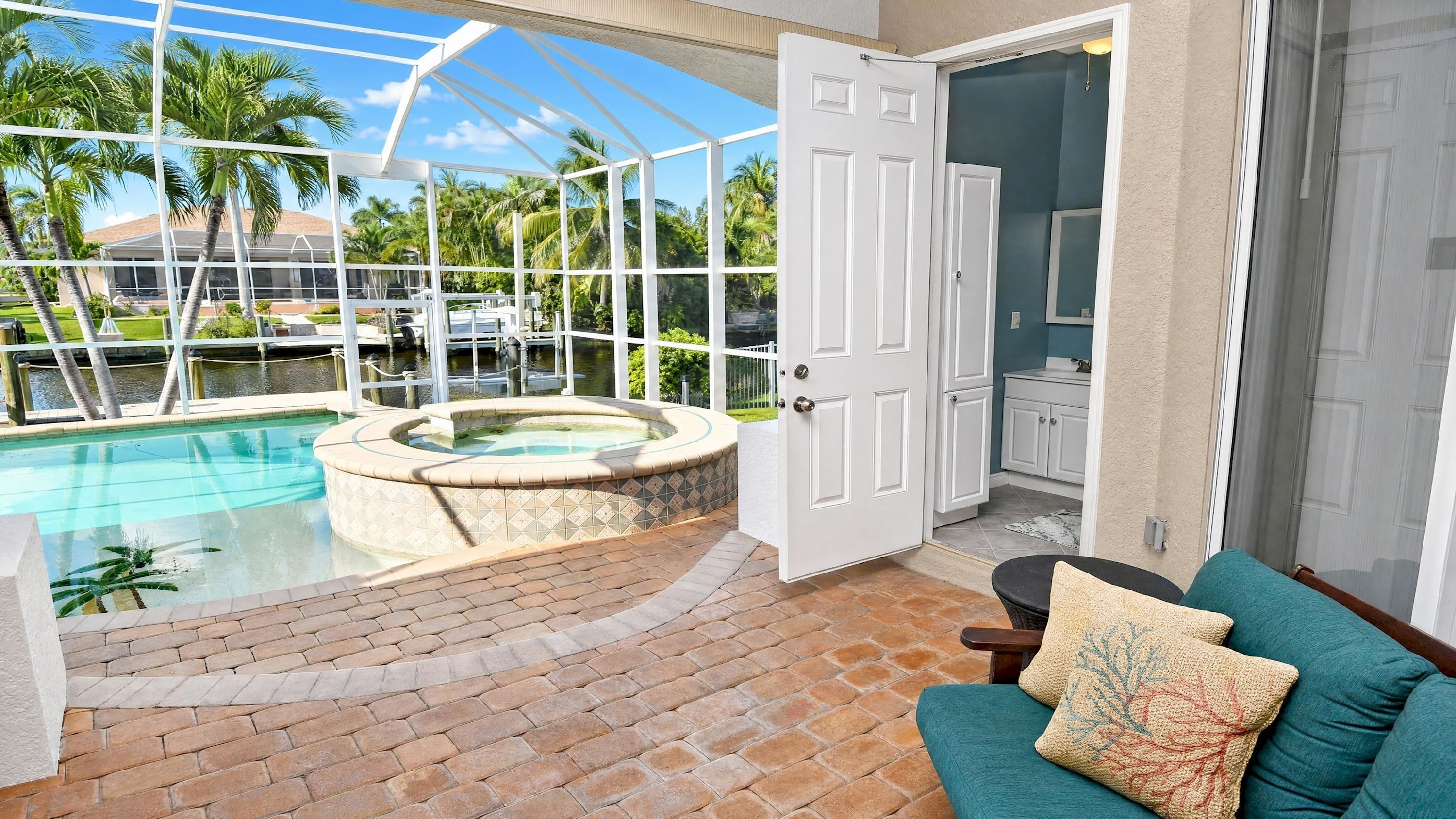 A pool area with a hot tub, a conservatory, and a view of palm trees.