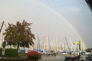 A marina with numerous boats docked, a rainbow in the sky, and a motorcycle parked on the side. - Holiday apartment with 2 bedrooms (Chieming - Arlaching)