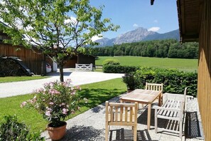 Eine Terrasse mit Holzmöbeln und Blick auf eine Berglandschaft.