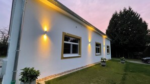 A modern building with exterior lighting, a well-maintained lawn, and a large tree. - Open, Bright Apartment (Halle (Westfalen))