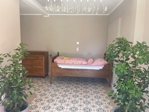 Ein Schlafzimmer mit einem hölzernen Bett, einer Kommode und zwei Topfpflanzen.