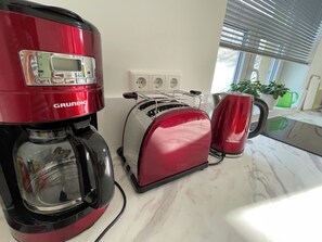 A kitchen with a red coffee maker, a toaster, and a kettle. - Open, Bright Apartment (Halle (Westfalen))