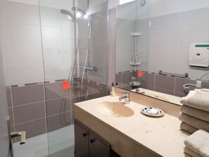 A bathroom with a glass shower enclosure, a sink with a mirror, and a towel rack. - Ground-floor apartment 100 meters from the beach, ideal for families, pets welcome (La Londe-les-Maures)