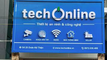 A building with a sign for 'HAPU APARTMENT by PHM' and another sign for 'techOnline' with various service icons.
